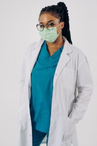 Doctor In Surgical Mask Standing With Her Hands In Pockets